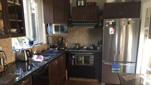 A kitchen with dark wooden cabinets, a stainless steel refrigerator, a microwave, an oven, and a gas stove.