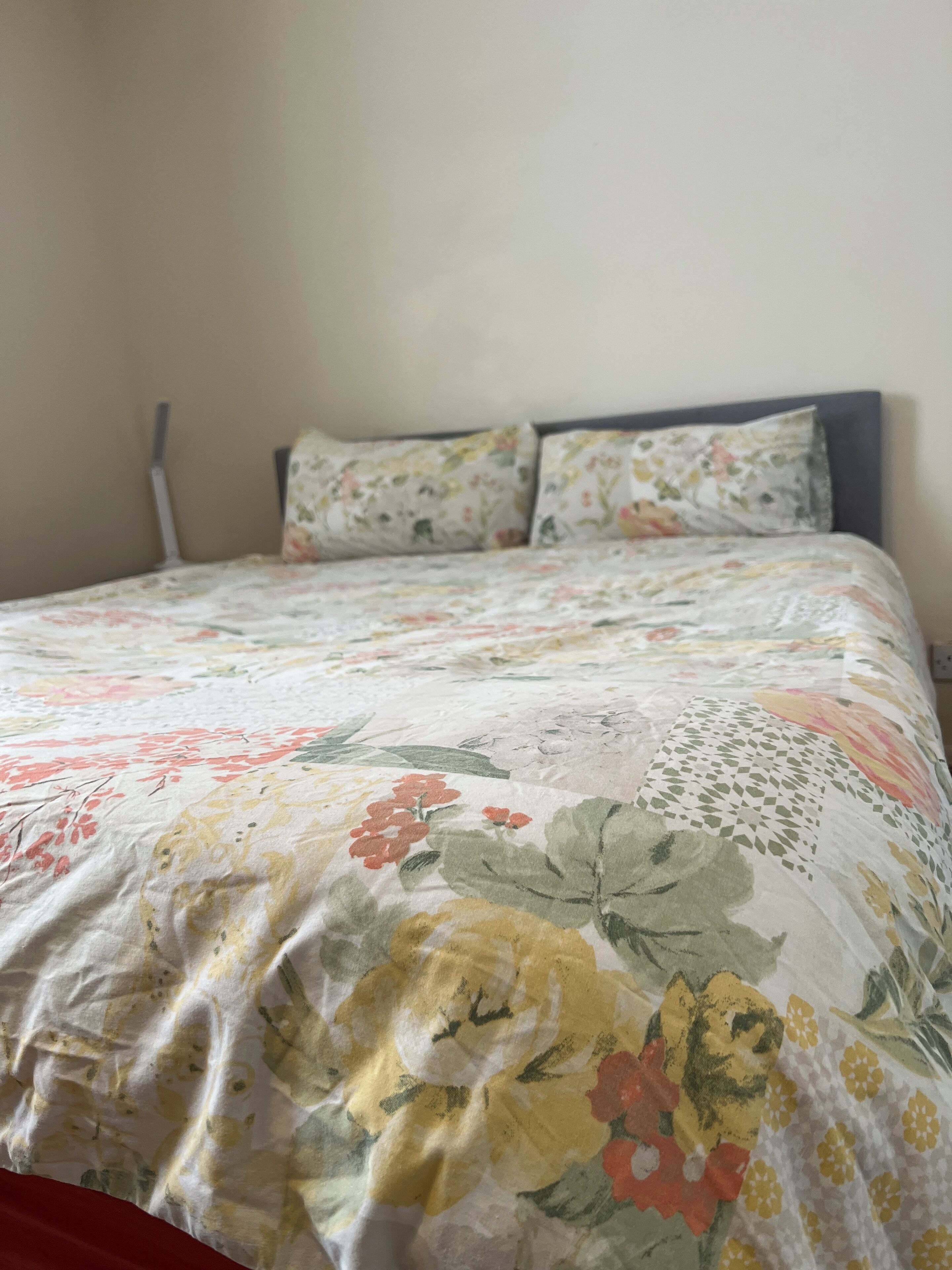 Un lit avec une couvre-lit à motifs floraux et deux oreillers assortis.