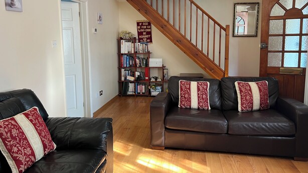 A living room with a wooden staircase, leather sofas, a bookshelf, and a door with frosted glass panels. - Spacious Home from Home! Perfect for Farnborough Airshow.  (Farnborough)