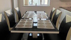 A dining area with a rectangular table, black and beige chairs, a window with curtains, and a white cabinet above the table. - Spacious Home from Home! Perfect for Farnborough Airshow.  (Farnborough)