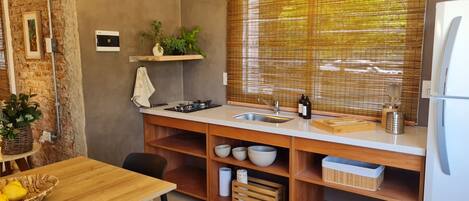 A compact kitchen with a wooden countertop, a gas stove, a sink, and a window with blinds.