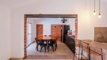 Un comedor con pared de ladrillo, una mesa de madera y sillas negras.
