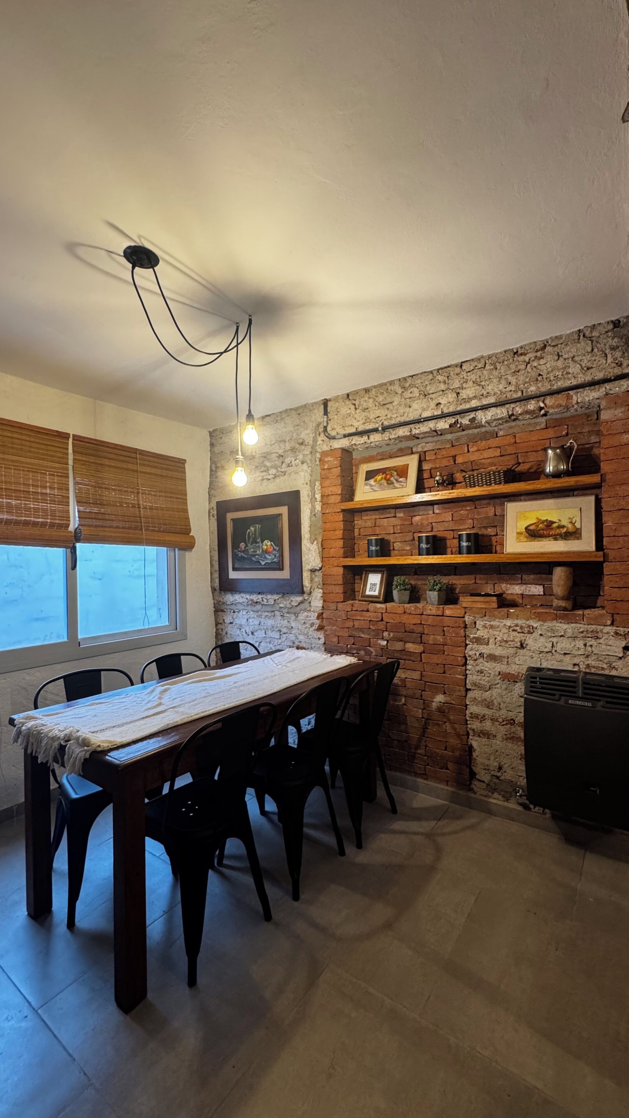 A dining area with a brick wall, wooden shelves, and a table with chairs.