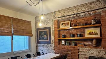 A dining area with a brick wall, wooden shelves, and a table with chairs.