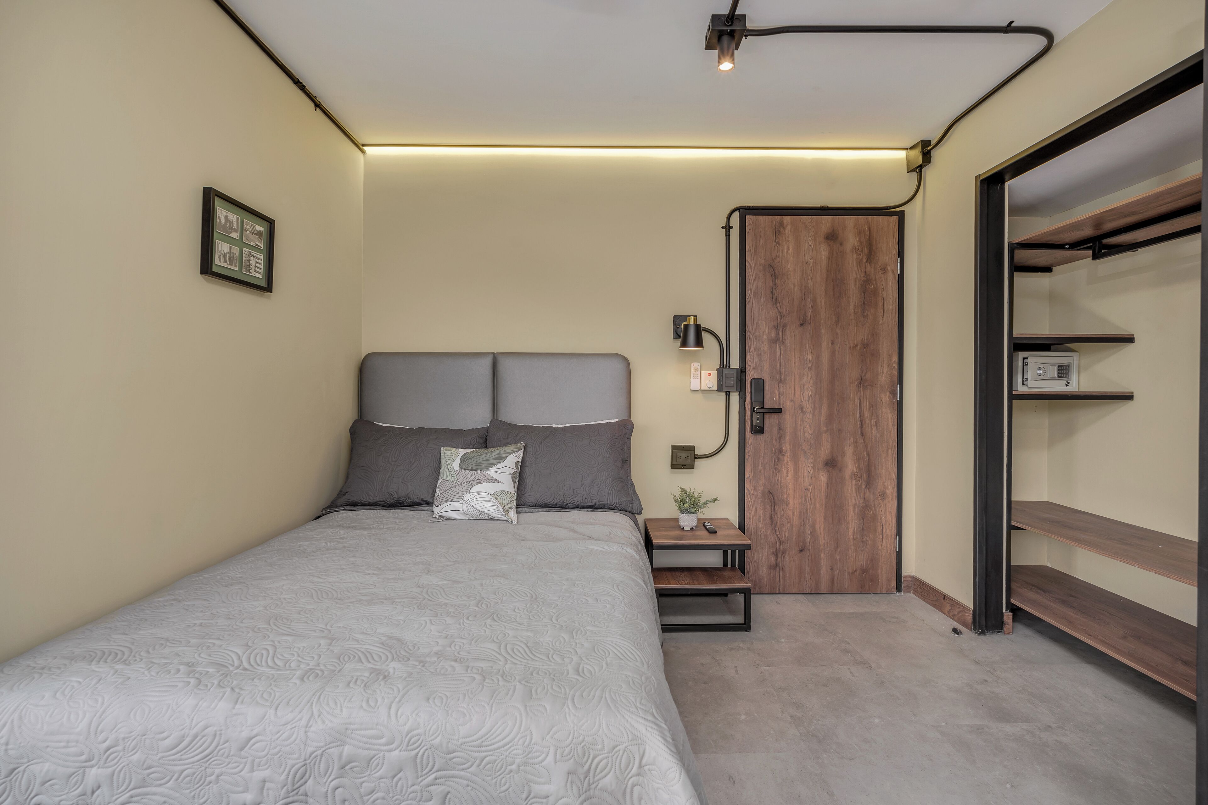 Een slaapkamer met een bed, nachtkastjes, een wandlamp, een ingelijste foto, een houten deur en inbouwplanken.