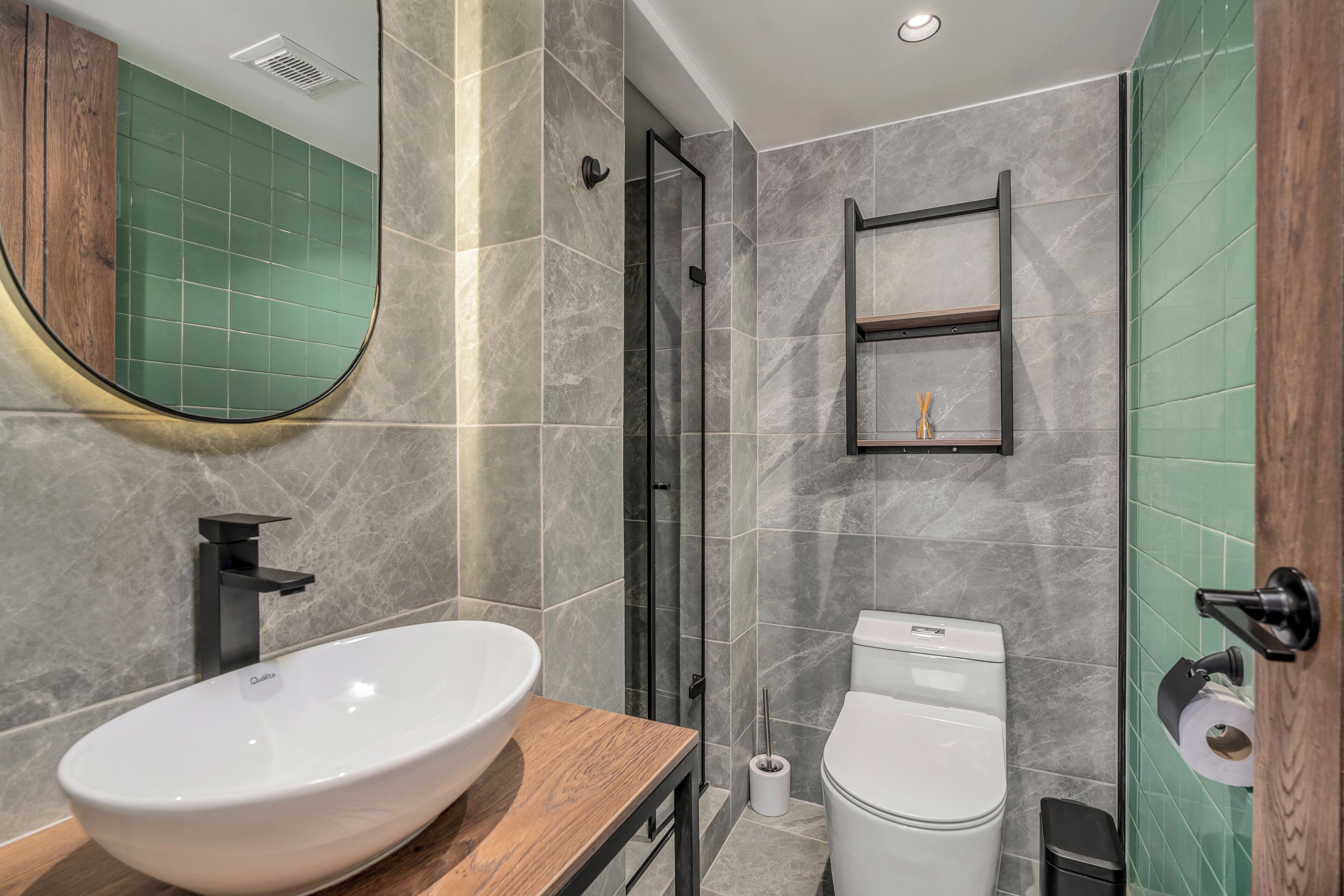 A modern bathroom with a large oval sink, a toilet, and a shower area.
