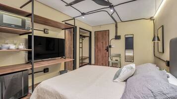 A modern bedroom with a bed, a TV, a mini-fridge, and a wardrobe.
