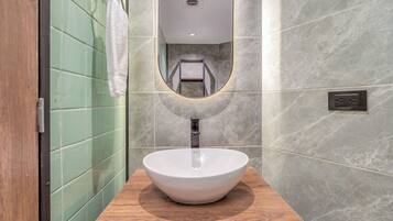 A bathroom with a white vessel sink, a wooden countertop, a towel hanging on a rack, and a mirror with a built-in light.