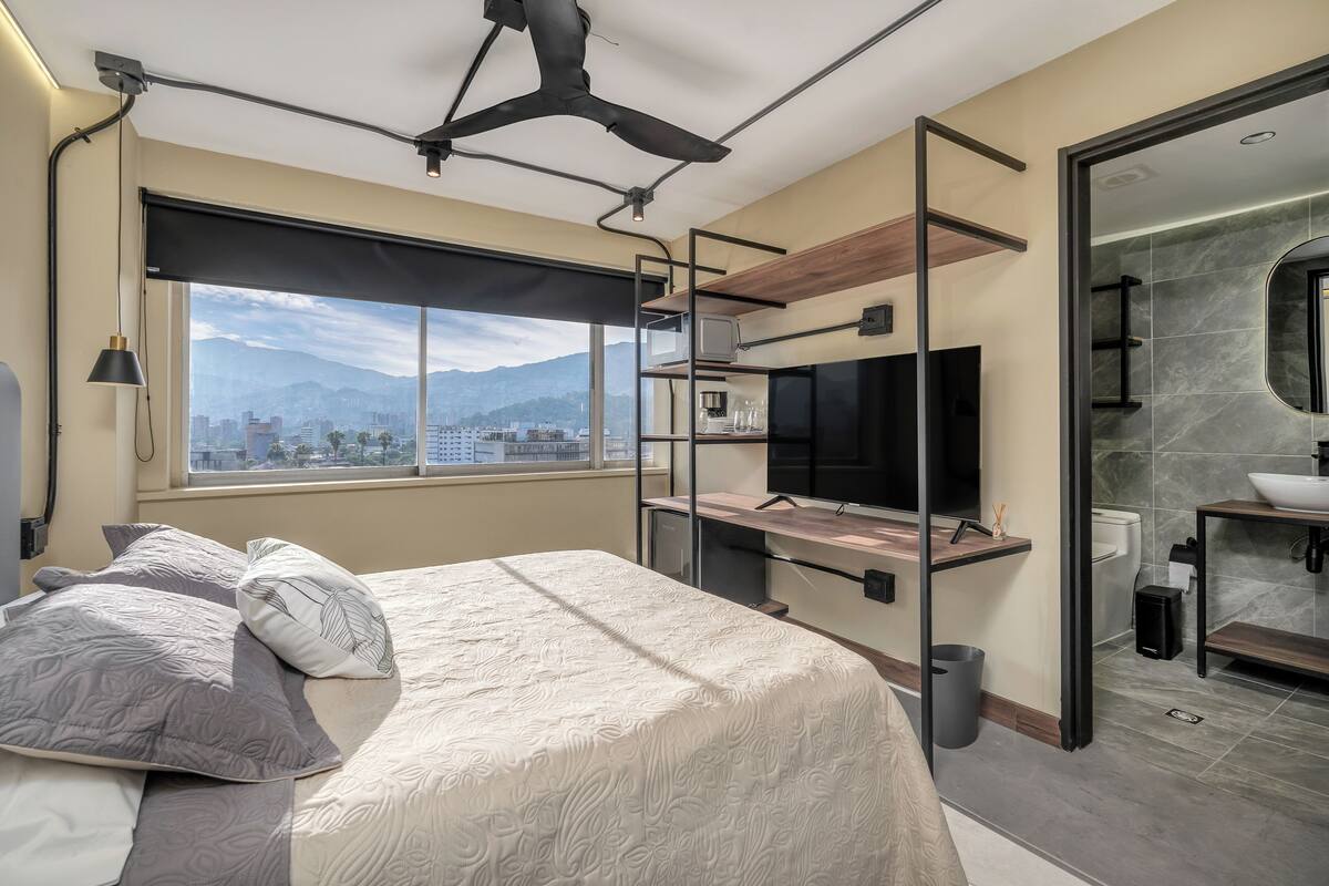 Een moderne slaapkamer met een bed, een televisie en uitzicht over de stad.