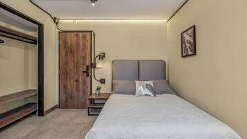 Ein Schlafzimmer mit Bett, Nachttisch, Lampe und einer Tür.