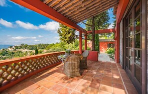 Relax in this serene outdoor space with a pergola, wicker chairs, and a table, offering a view of the surrounding hillside.