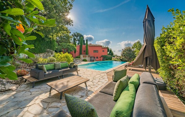 Relax by the serene pool surrounded by lush greenery and comfortable seating.