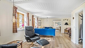 A spacious living room with a blue sofa set, a black leather chair, and a wooden coffee table.
