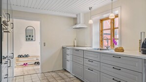 A kitchen with grey cabinets, a window with wooden frames, a sink, and a loaf of bread on the counter.