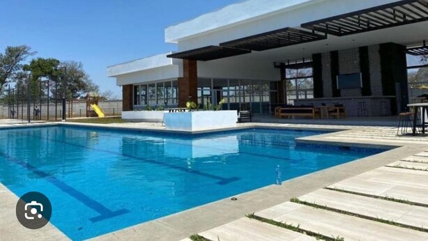 Un edificio moderno con piscina, zona de estar al aire libre y un patio cubierto.