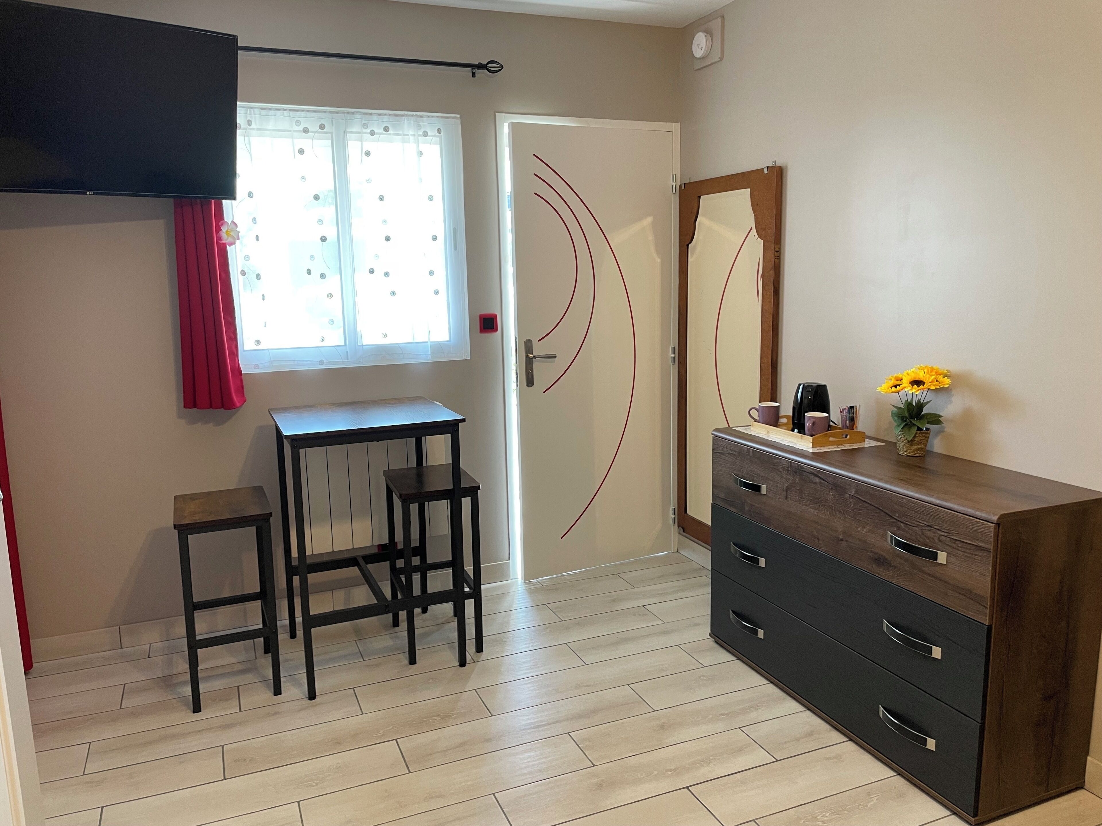 Una habitación con escritorio, dos sillas, cómoda y espejo.