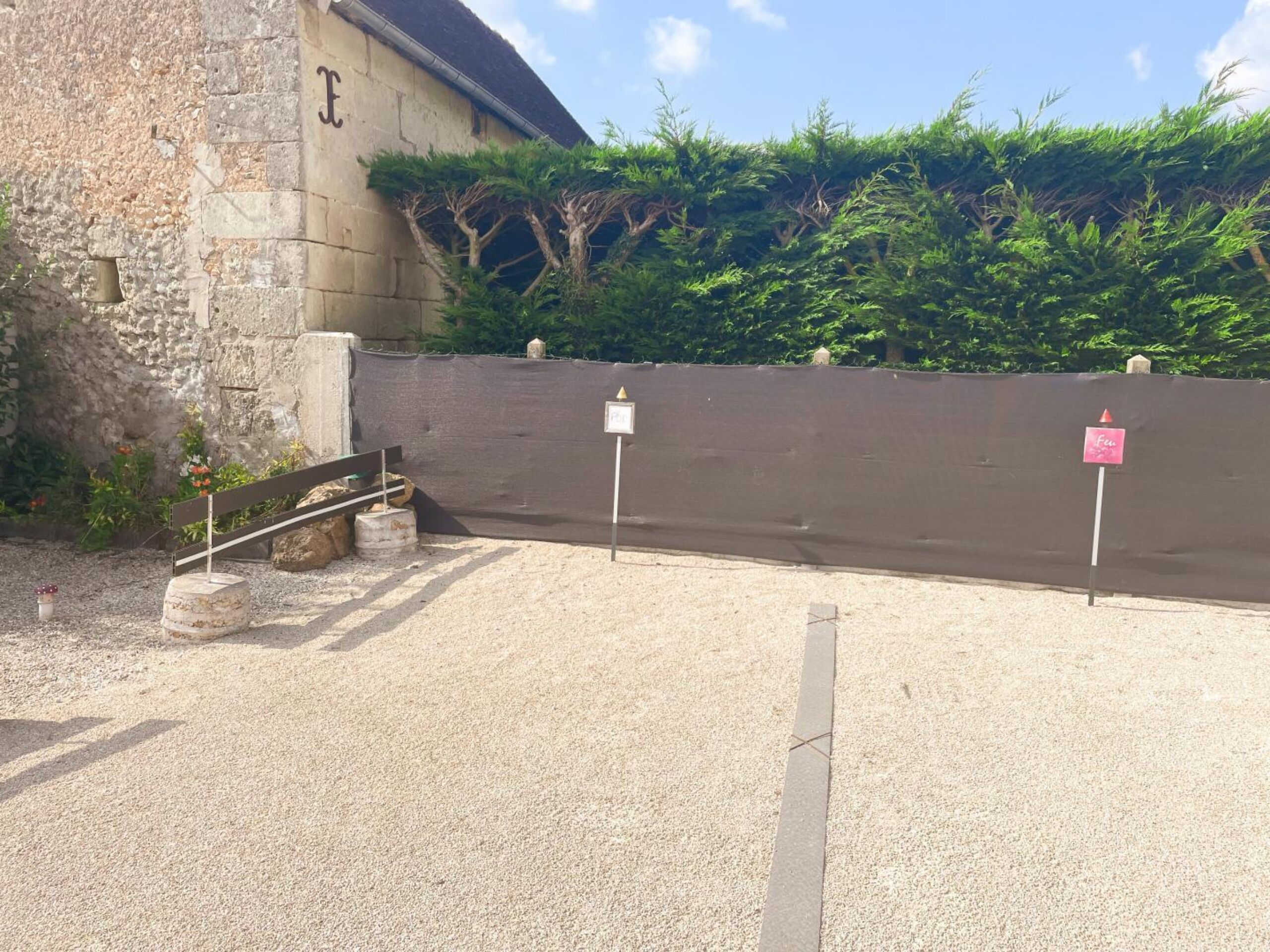 Un aparcamiento de grava con un muro de piedra y una valla de metal.