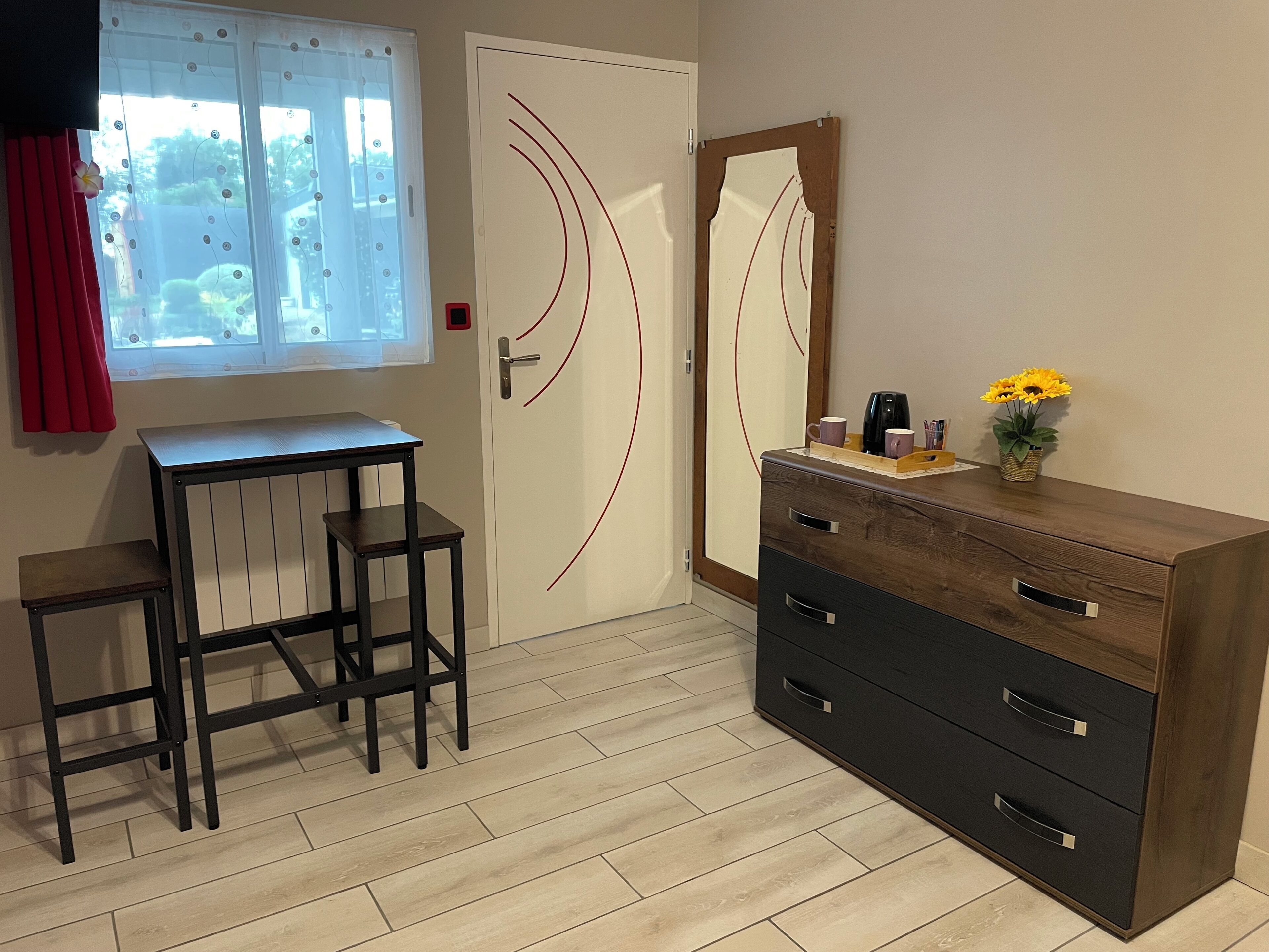 Una habitación con un escritorio de madera, dos sillas, un aparador y una ventana con cortinas.