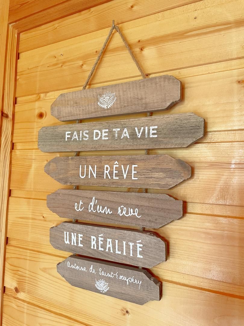 Een houten bord met Franse tekst aan een houten muur.