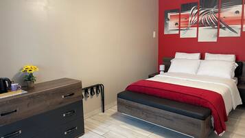 A modern bedroom with a bed, bedside tables, a dresser, and a wall-mounted artwork.