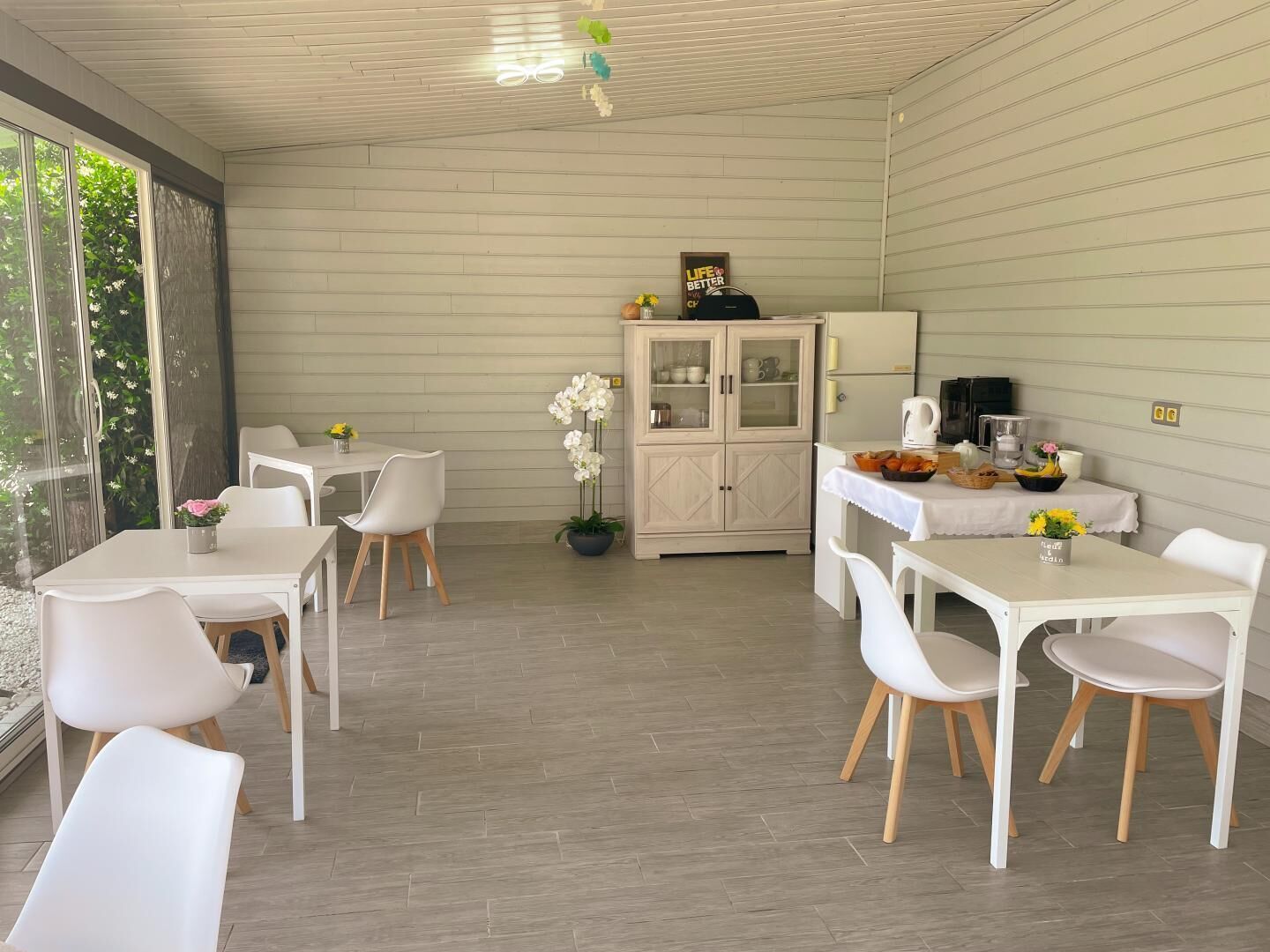 Una cocina moderna con armarios blancos, un comedor con sillas blancas y vistas a través de amplios ventanales.
