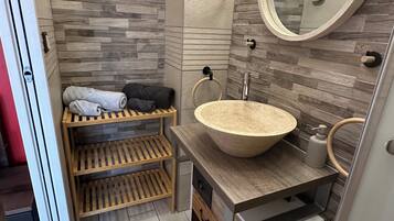 A modern bathroom with a wooden vanity, a round sink, and a large mirror.