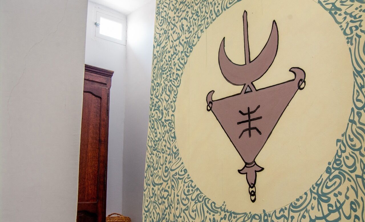 A wall with a geometric pattern and a symbol resembling a trident.