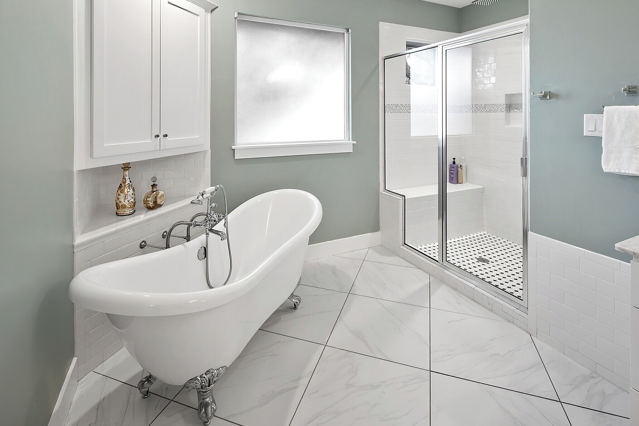 Ein Badezimmer mit freistehender Badewanne, einer in Glas abgeschirmten Dusche und weiß gefliesten Wänden.