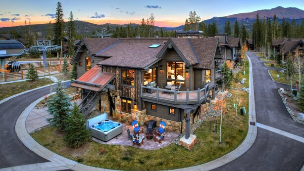 Ein modernes, zweistöckiges Haus mit einer großen Terrasse, einem Whirlpool und einem Kamin.