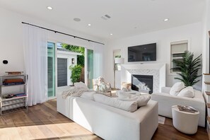 Ein modernes Wohnzimmer mit Kamin, weißen Sofas und einer Bücherwand.