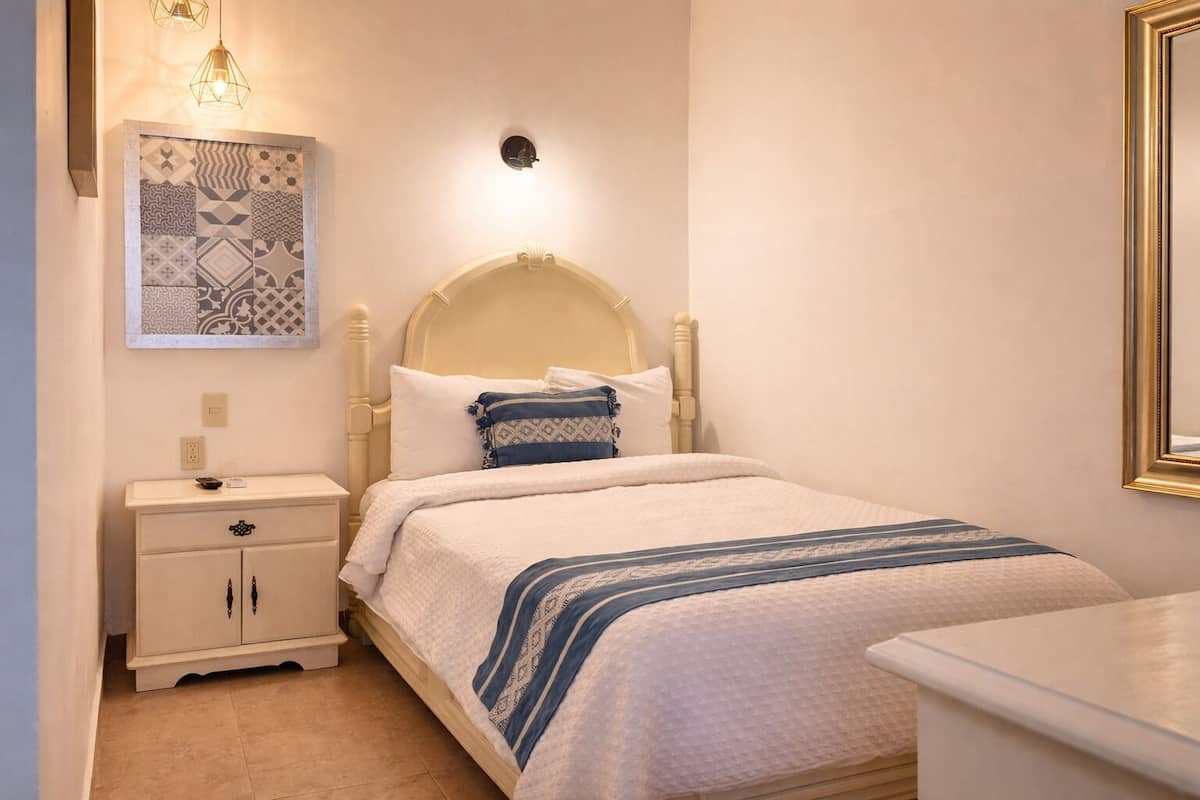 A neatly arranged bedroom with a bed, bedside table, and a wall-mounted light fixture.