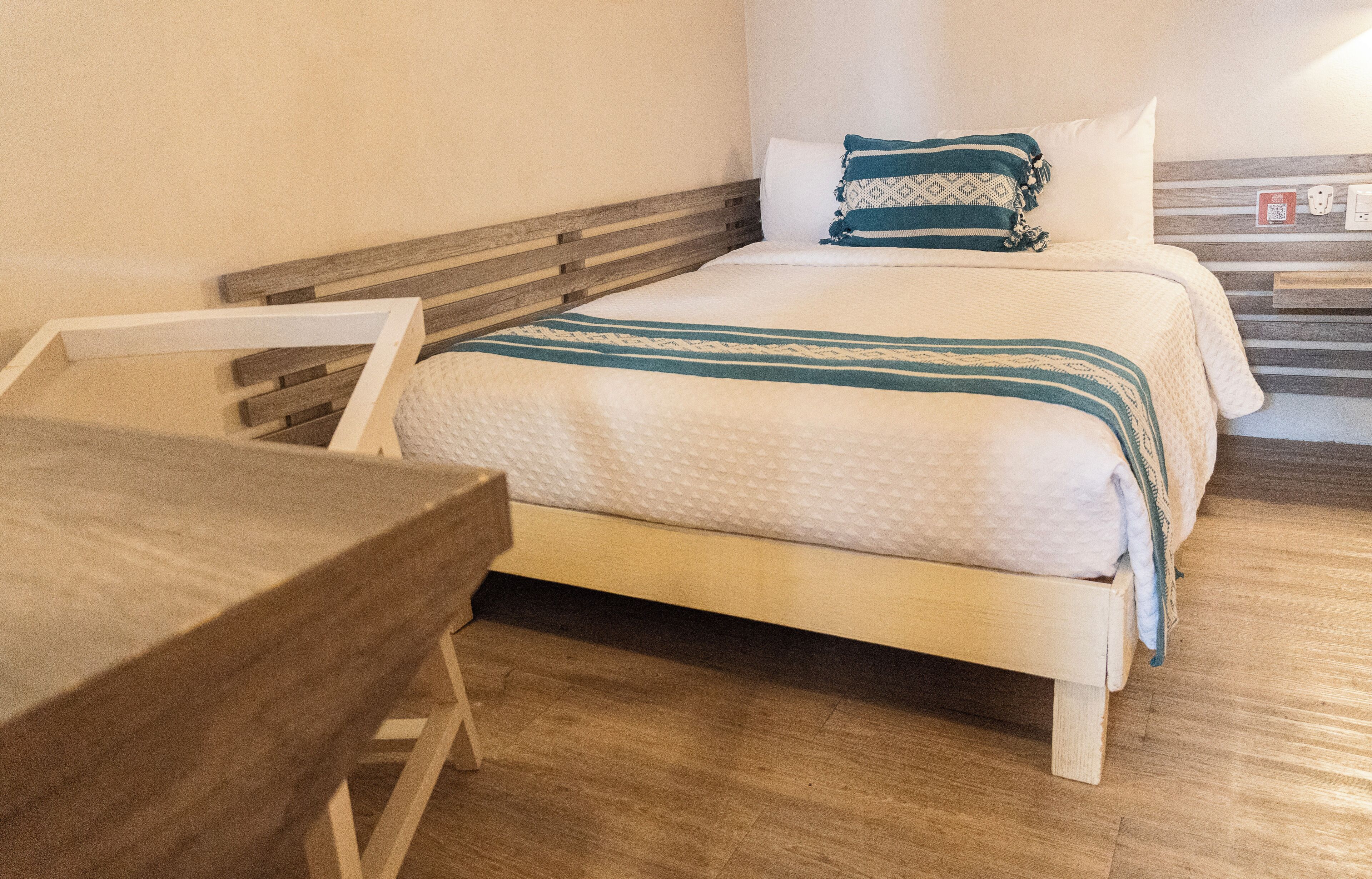 Un lit avec une tête de lit en bois, une table de chevet et une prise électrique fixée au mur.