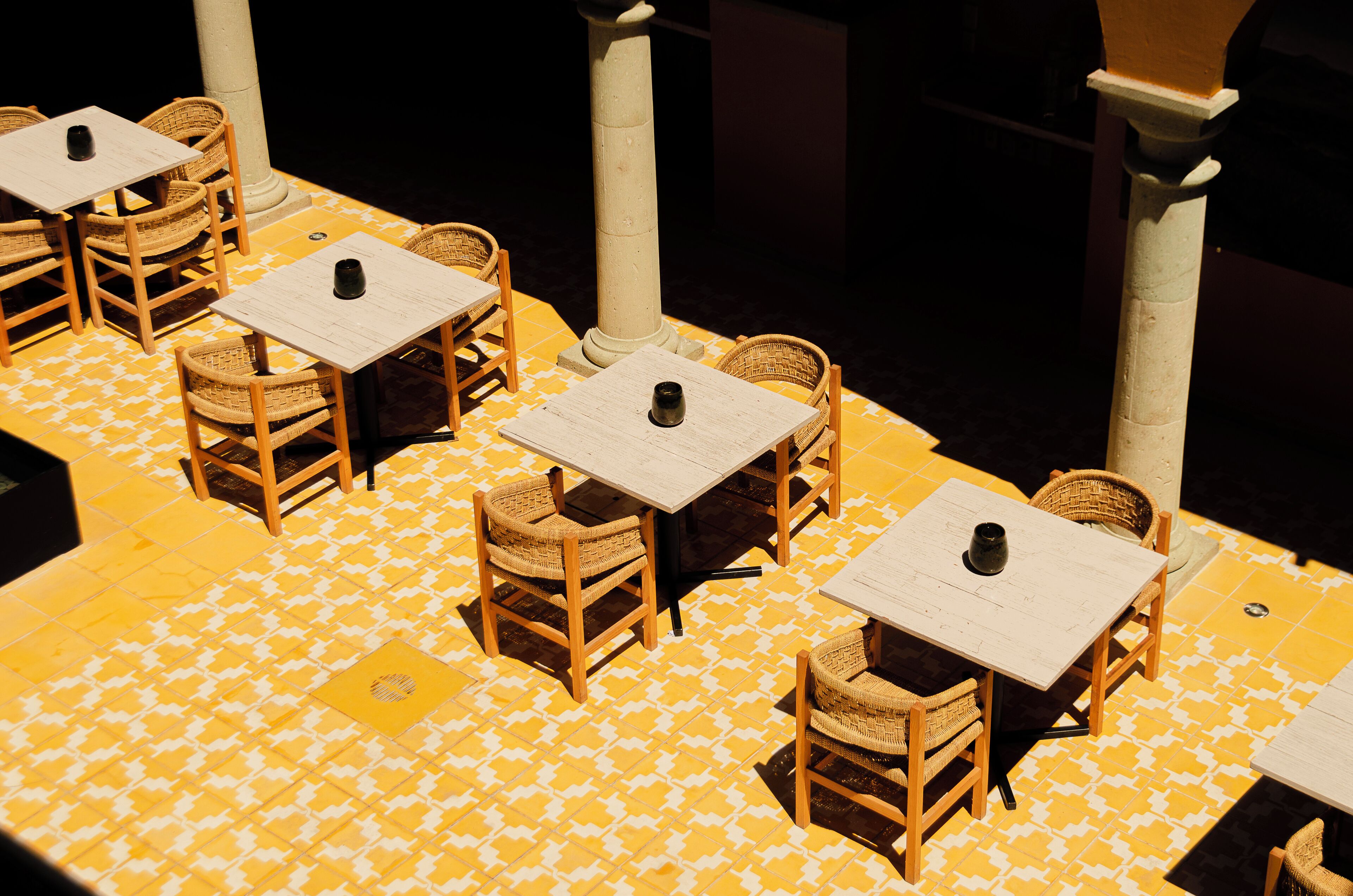 A dining area with tables and chairs, a patterned floor, and columns.