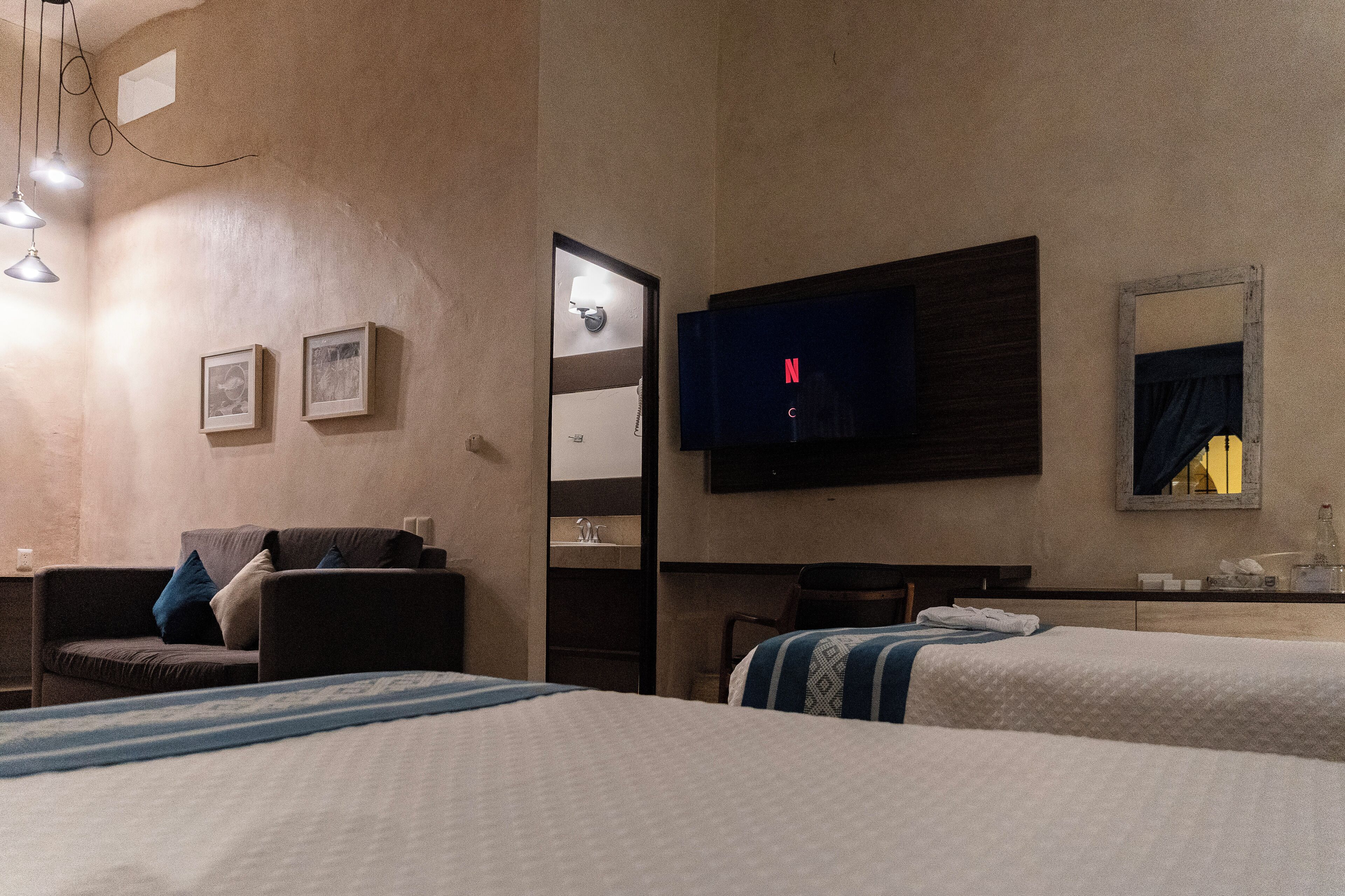 A hotel room with two beds, a TV, a desk, and a mirror.