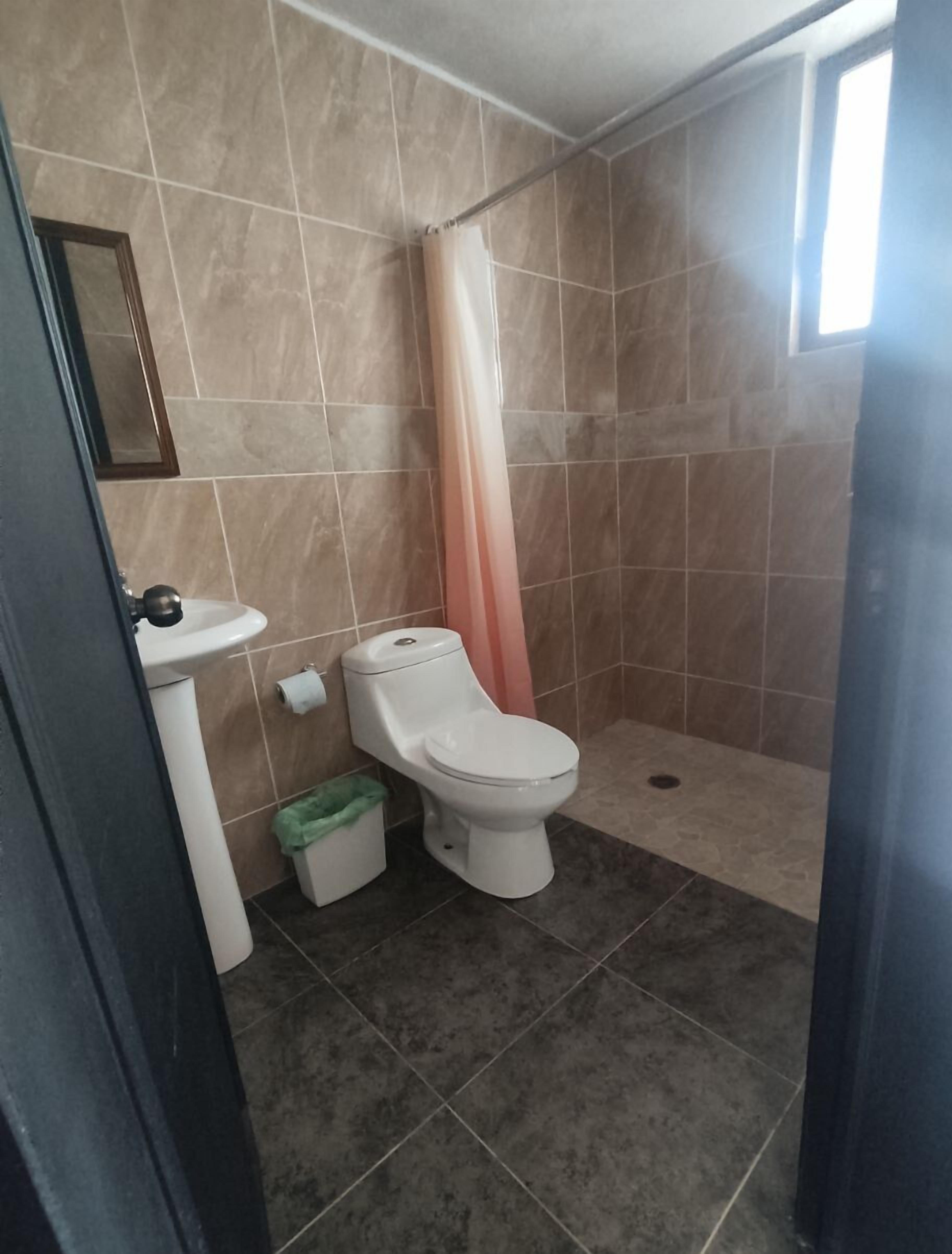 Et badeværelse med toilet, håndvask og bruseområde.