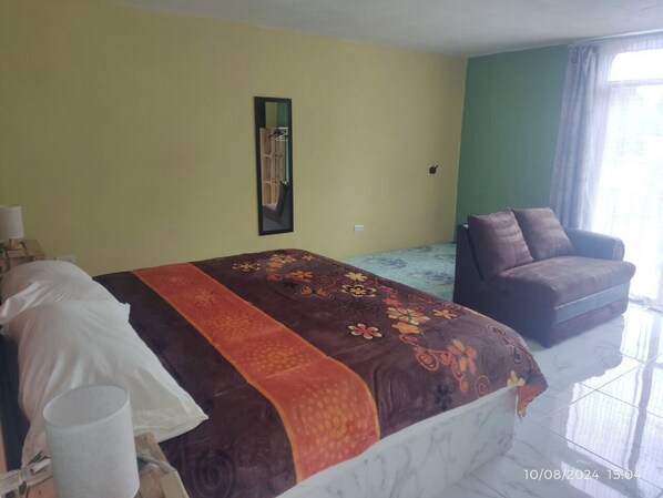 A hotel room with a bed, a chair, and a mirror on the wall.