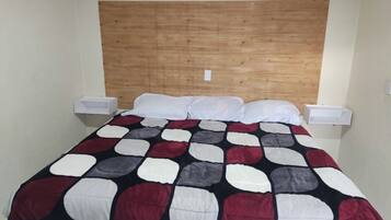 A single bed with a wooden headboard, white pillows, and a patterned bedspread.