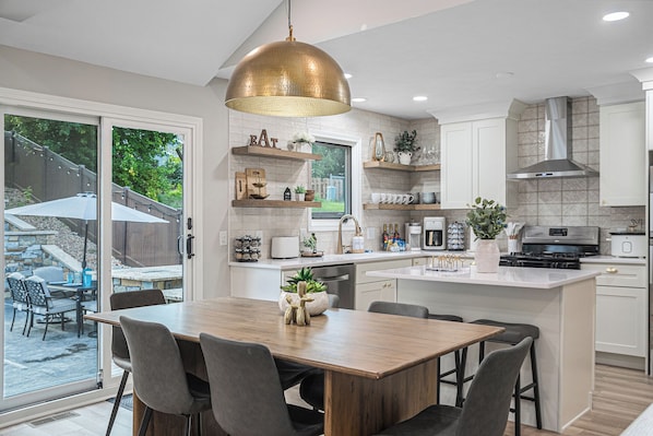Una cocina moderna con una isla central, estantes empotrados y una lámpara colgante grande.