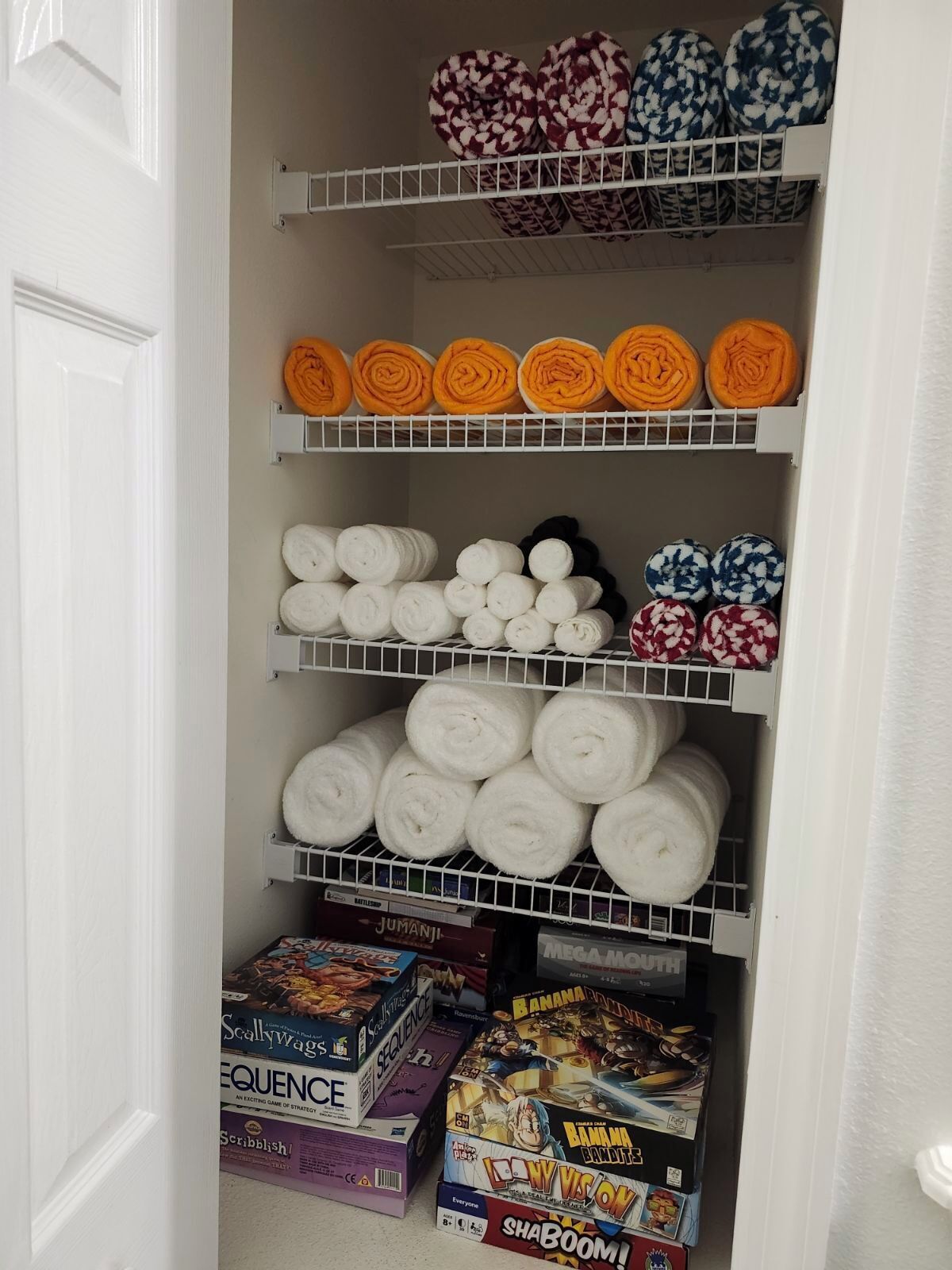 Un depósito con estantes que guardan toallas enrolladas de diversos colores y diseños, y juegos de mesa.