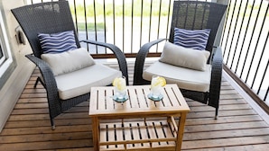 Two wicker chairs with cushions and a wooden table with two glasses of iced tea and lemon slices. - Beautiful 3 Bedroom House w/ Hot Tub, Sauna & Private Yard - 2 Minutes to RMR (Revelstoke)