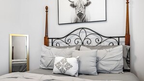 A neatly made bed with a headboard, a mirror, and a framed picture on the wall. - Cozy 2bdr/1br Home near downtown (Sacramento)