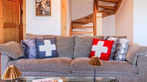 A cozy living room with a sofa, a lamp, and a painting of a cow. - Chalet Aurore by Interhome (Nendaz)
