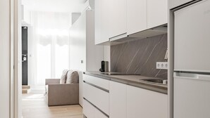 A modern kitchen with white cabinets, a marble backsplash, and a built-in oven. - Charming Madrid Castilla I - Studio for 4 people (Madrid)