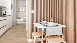 A modern kitchen with white cabinets, a grey countertop, and a wooden dining table with two chairs. - Charming Madrid Castilla I - Studio for 4 people (Madrid)