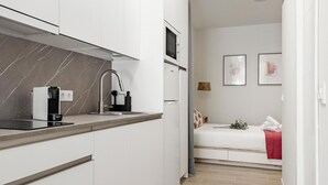A modern kitchen with white cabinets, a marble backsplash, and a built-in microwave. - Charming Madrid Castilla II - Studio for 4 people (Madrid)