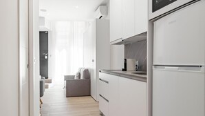 A modern kitchen with white cabinetry, a built-in oven, and a coffee maker. - Charming Madrid Castilla II - Studio for 4 people (Madrid)