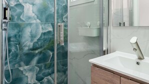 Une salle de bain avec une douche à parois de verre, un lavabo blanc et un miroir.