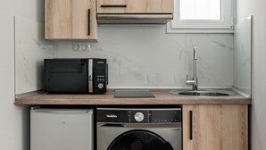 Une cuisine compacte avec des meubles en bois, un four à micro-ondes encastré, un évier et un lave-vaisselle à chargement frontal.