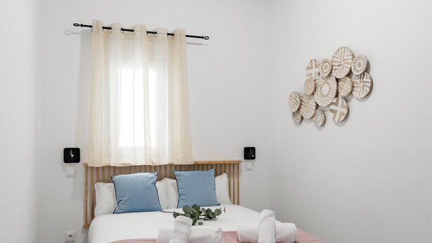 Un lit bien fait, avec une couverture rose, des oreillers bleus et des serviettes blanches.