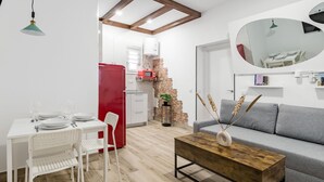 En moderne stue med en grå sofa, et træ sofabord og et hvidt spisebord med stole.